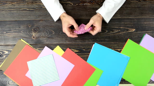 Man-folding-origami-from-pink-paper.