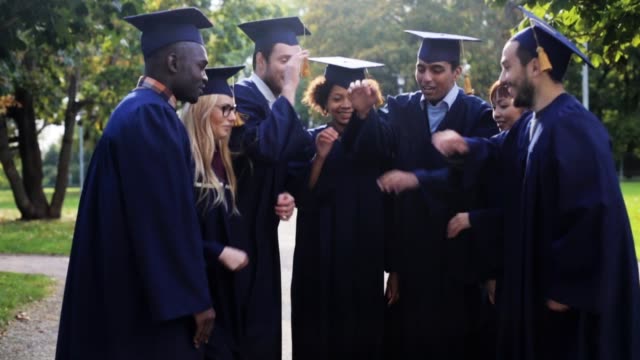 happy-students-in-mortar-boards-with-hands-on-top