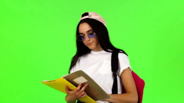 Glückliche-junge-Schülerin-posiert-mit-ihren-Büchern-und-Rucksack
