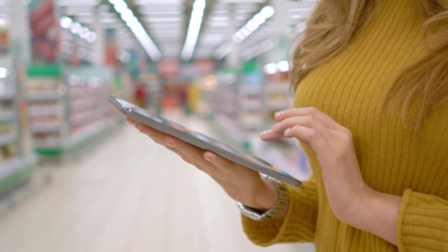 Mujer-cliente-utilizando-una-tableta-digital-en-el-supermercado