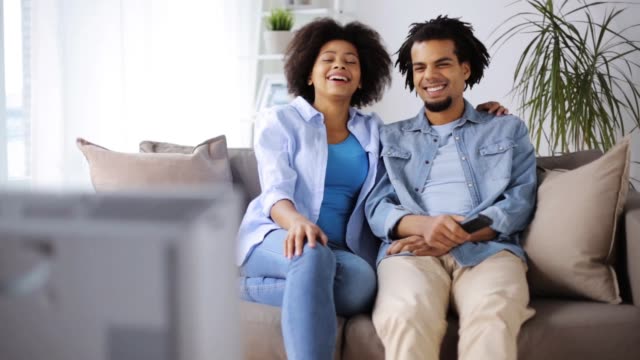 glücklich-lächelnde-paar-vor-dem-Fernseher-zu-Hause