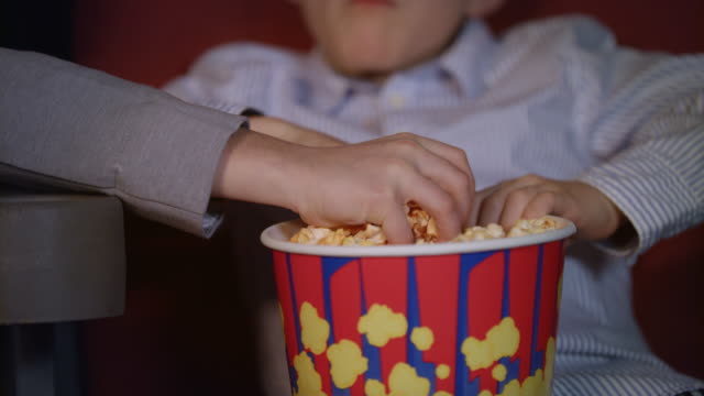 Kinderhände-Papierkasten-Popcorn-wegzunehmen.-Kino-Essen-für-Kinder