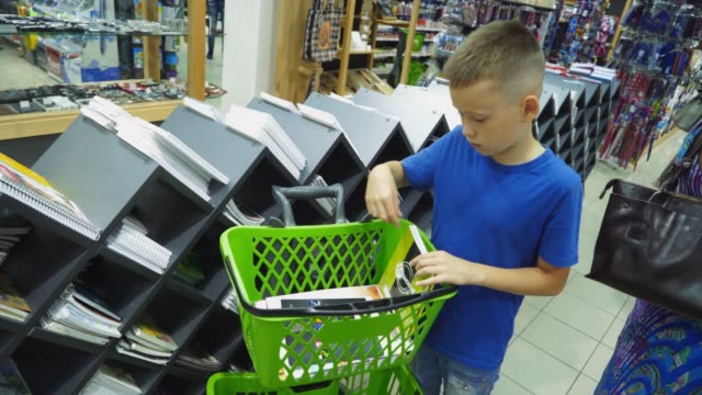 Niño-comprando-diferentes-productos-en-la-tienda-de-artículos-de-papelería.