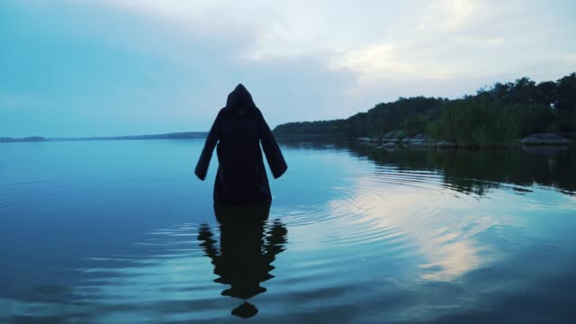 Evil-witch-in-black-cloak-with-hood-in-the-river.