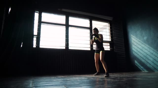 silueta-de-joven-hermosa-mujer-boxeo-entrenamiento-en-gimnasio-de-perforación