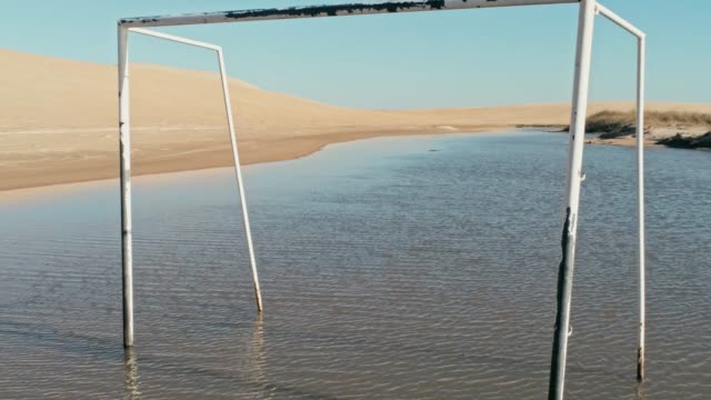 Luftaufnahmen-von-einem-schönen-blauen-Lagune-neben-den-Dünen-der-Wüste-Sand-mit-einem-Fußball-Tor-im-Wasser