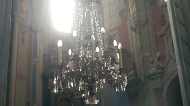 a-luxurious-chandelier-hangs-in-the-middle-of-a-catholic-cathedral-on-the-background-of-frescoes.