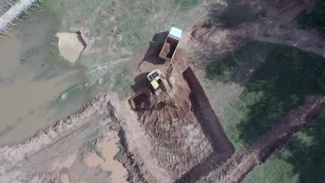 Aerial:-static-view-of-an-excavator-loading-earth-into-a-small-truck