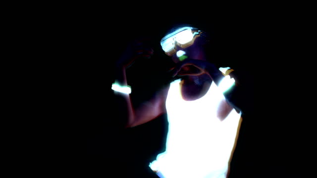 Woman-with-UV-face-paint,-glowing-clothing,-glowing-glasses,-bracelet-dancing-in-front-of-camera,-half-body-shot.-Asian-woman.-Glitch-effect.-Women.