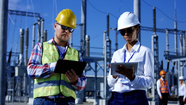 Two-electrical-workers-on-tablets-outside