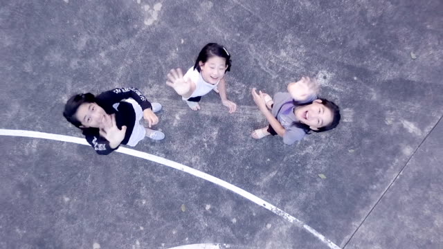 Aerial-view-of-girls-enjoy-playing-at-basketball-yard-in-evening