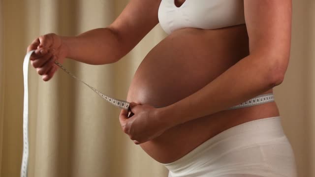 Mujer-embarazada-comprueba-su-vientre-con-cinta-métrica