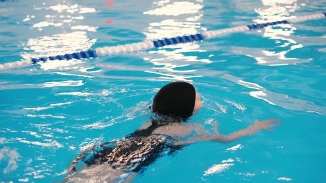 clases-de-natación-para-niños-en-la-piscina---hermosa-chica-de-piel-clara-nada-en-el-agua