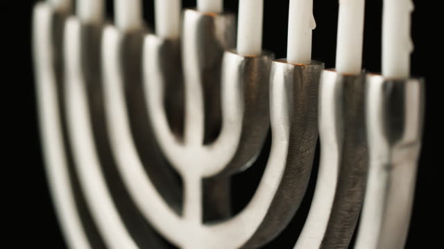 Close-up,-shallow-depth-of-field-tilt-shot-of-silver-menorah-at-an-angle,-with-white-lit-candles