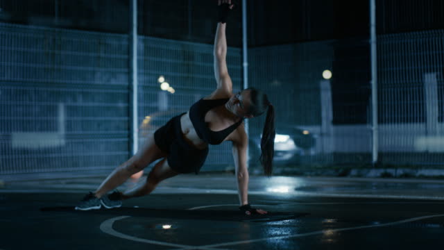 Schöne-sportliche-Fitness-Girl-Doing-Push-Up-Übungen.-Sie-ist-ein-Training-in-einem-eingezäunten-Basketballfeld-im-freien-tun.-Nacht-Aufnahmen-nach-Regen-in-einer-Wohngegend.