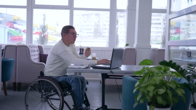 online-shopping,-invalid-spectacles-in-wheelchair-with-credit-card-makes-payment-in-Internet-using-smart-computer-technology-during-remote-business-management