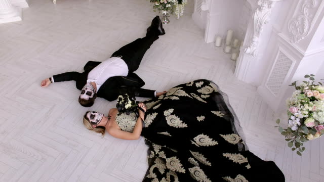 A-couple-with-makeup-on-their-face-lie-on-the-floor-in-a-vintage-room.-Halloween