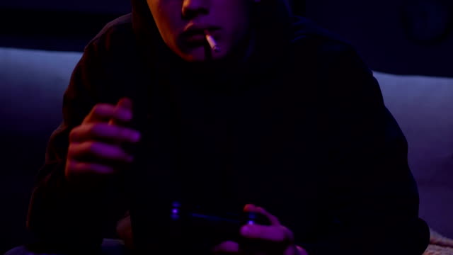 Adolescente-fumando-cigarrillo-y-jugando-videojuego,-usando-joystick,-procrastinación