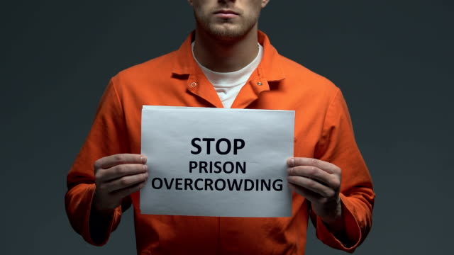 Stop-prison-overcrowding-phrase-on-cardboard-in-hands-of-Caucasian-prisoner