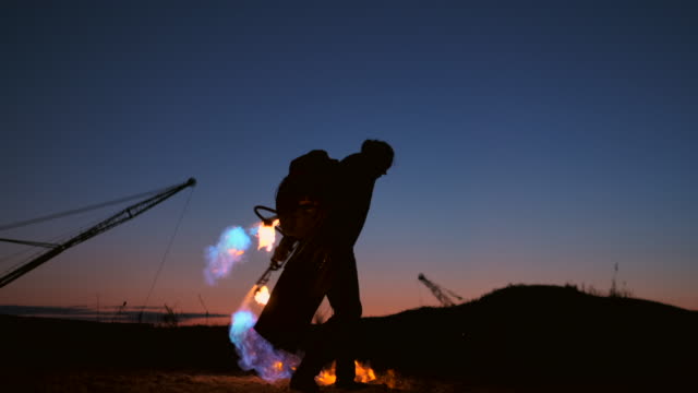 A-man-with-a-flamethrower-at-sunset-in-slow-motion.-Costume-for-zombie-Apocalypse-and-Halloween.