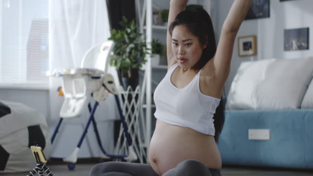 Schwangere-Frau-beobachten-Tutorial-Video-während-des-Trainings