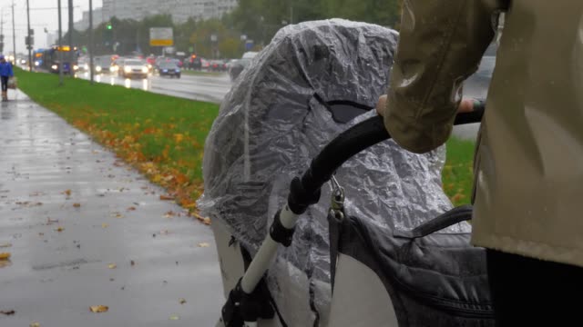 Mamá-caminando-con-el-bebé-en-el-día-lluvioso-del-otoño