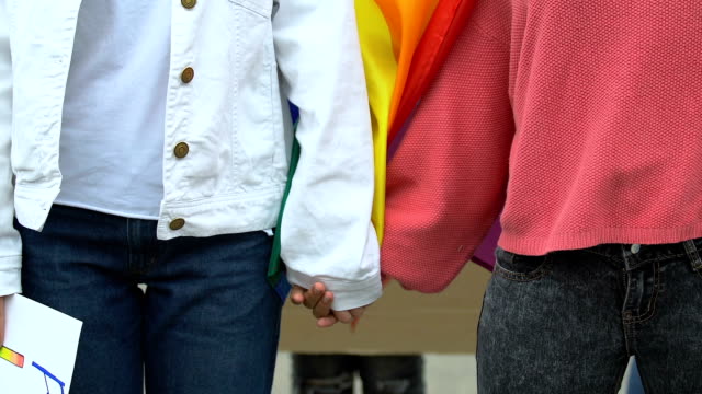 Pareja-femenina-tomando-las-manos-sosteniendo-cartel-de-derechos-LGBT,-apoyo-para-el-matrimonio-gay
