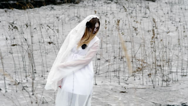 Die-junge-Frau-mit-beängstigend-Make-up-der-toten-Braut-für-Halloween-in-weißen-Kleid.-4K