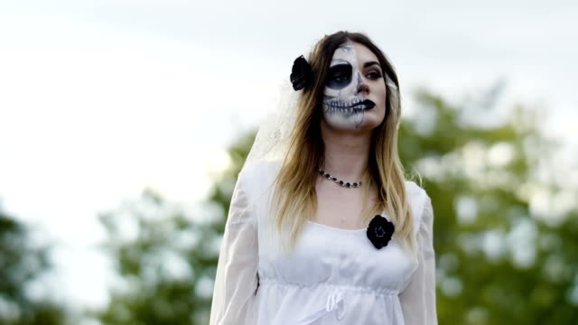 Die-junge-Frau-mit-gruseligem-Make-up-für-Halloween-in-einem-weißen-Brautkleid.-4K