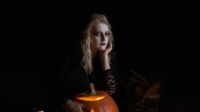 Imagen-de-Halloween-.-La-joven-bruja-con-ropa-negra-sostiene-calabaza-en-sus-manos.