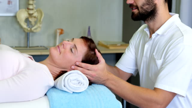 Physiotherapeuten,-die-eine-Frau-Kopfmassage-verleihen