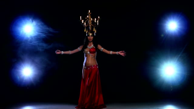 Attractive-belly-dancer-woman-dancing-with-candles-on-her-head,-black,-smoke