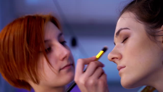 Concept-of-beauty-and-fashion.-Professional-makeup-artist-applying-cosmetics-on-model-face.-Zoom-out