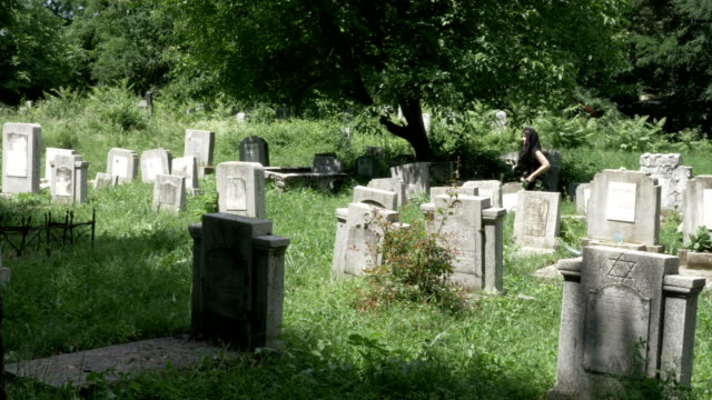 Young-woman-dressed-in-funeral-clothes-walking-in-cemetery-among-the-graves