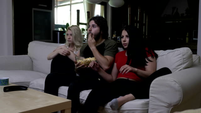 Roommates-eating-popcorn-at-home-get-scared-while-watching-horror-movie