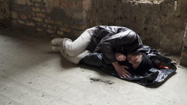 Obdachloser-schläft-auf-Abfallsack-in-verlassenen-Gebäude
