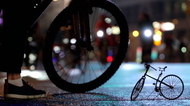 Mucho-paseo-de-ciclistas-durante-la-noche-ciclismo-desfile-bicicletas-en-blur-por-calle-contra-fondo-de-modelo-a-pequeña-escala-de-timalapse-de-bicicletas-de-la-ciudad-de-noche-iluminada.-Multitud-de-gente-en-bicicleta.-Tráfico-de-bicicleta.-Estilo-de-vida-saludable-concepto-de-deporte.-Luces-brillantes.-Bajo
