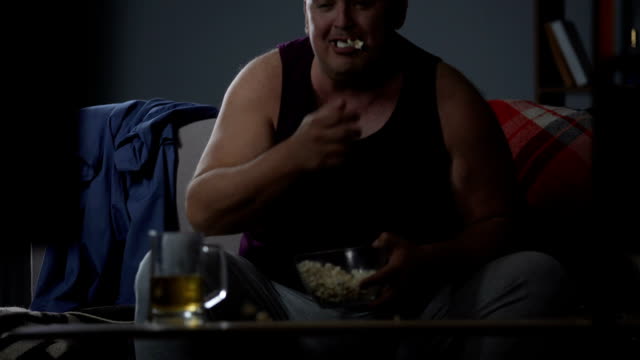 Man-watching-TV-with-popcorn-and-beer,-messy-careless-lifestyle,-food-addiction