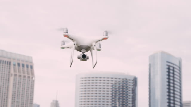 Quadcopter-drone-with-camera-on-gimbal-flying-in-the-city-sky,-shot-in-slow-motion