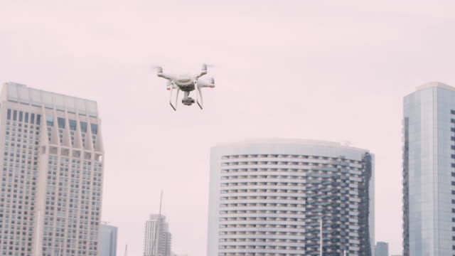 Quadrocopter-Drohne-mit-Kamera-auf-Gimbal-fliegen-in-den-Himmel-der-Stadt,-in-Zeitlupe-erschossen