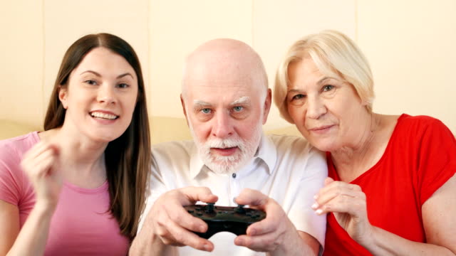 Älteres-Paar-und-Tochter-Gamer-spielen-Video-Spiel-zu-Hause.-Glückliche-Familie,-die-Zeit-zusammen-genießen