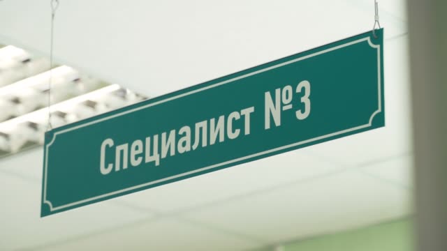 Green-plastic-sign-under-ceiling-with-cyrillic-text-sais-specialist-number-three