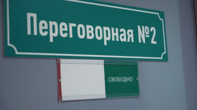 Female-hand-moves-plate-to-occupied-on-door-with-russian-text-meeting-room