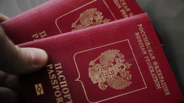 Man`s-hand-puts-two-international-passports.-Close-up