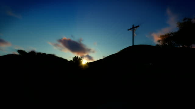 Christian-woman-praying-at-Jesus-cross,-sunset,-panning,-4K