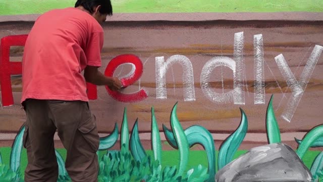 Mural-painter-draws-a-letter-e-on-school-wall.-time-lapse