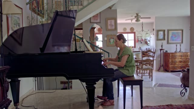 Old-woman-playing-a-grand-piano-at-her-home