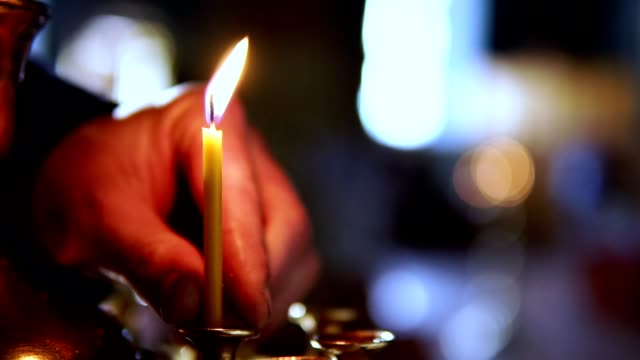 Eine-Person-stellt-eine-Kerze-auf-den-Altar-in-einer-orthodoxen-Kirche