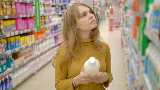 Young-women-choosing-household-chemicals-in-supermarket.