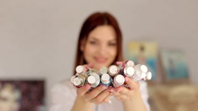 Girl-in-an-art-studio-holds-a-of-tubes-with-paints